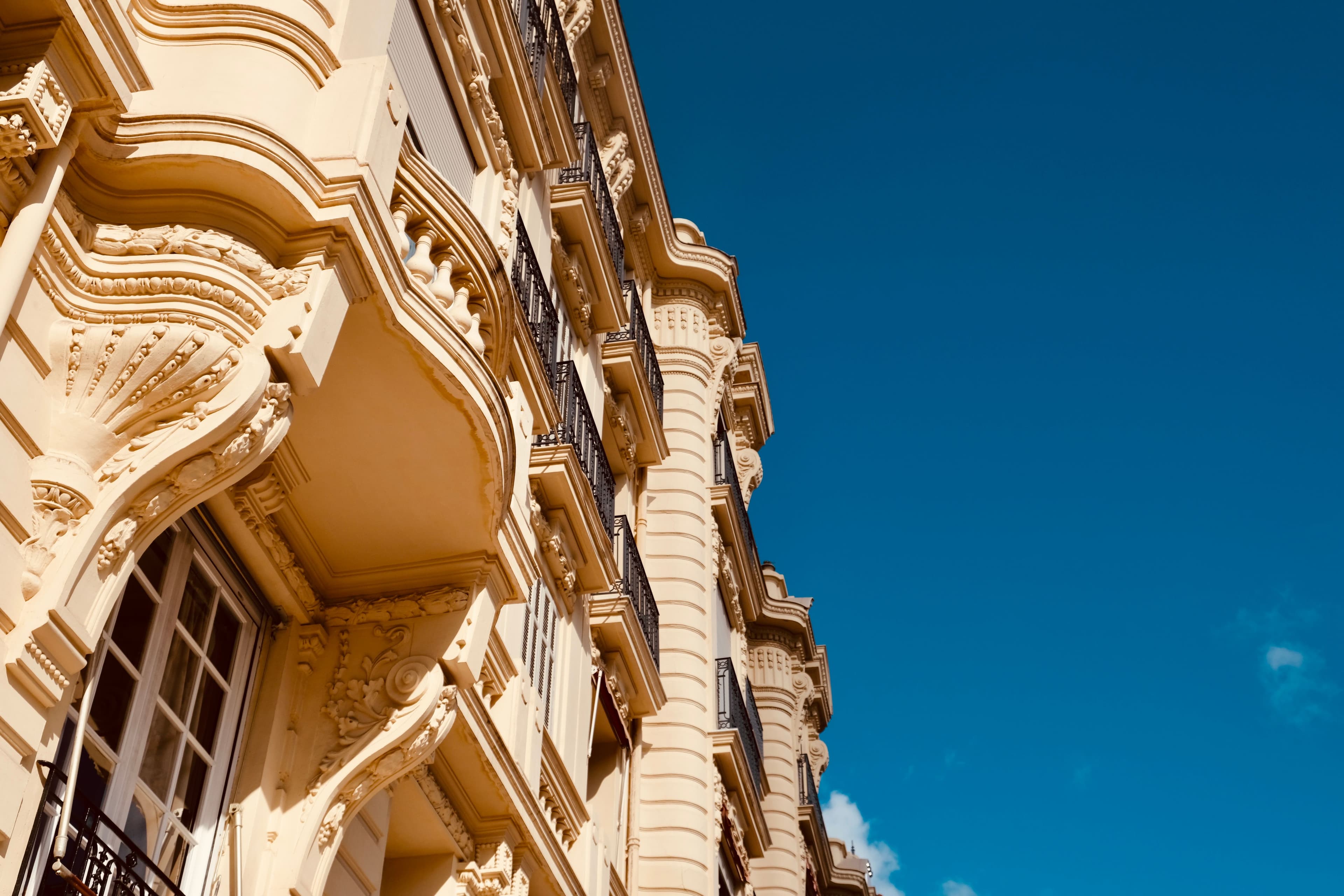 Façade haussmannienne parisienne avec balcons, vue en contre-plongée sous un ciel bleu
