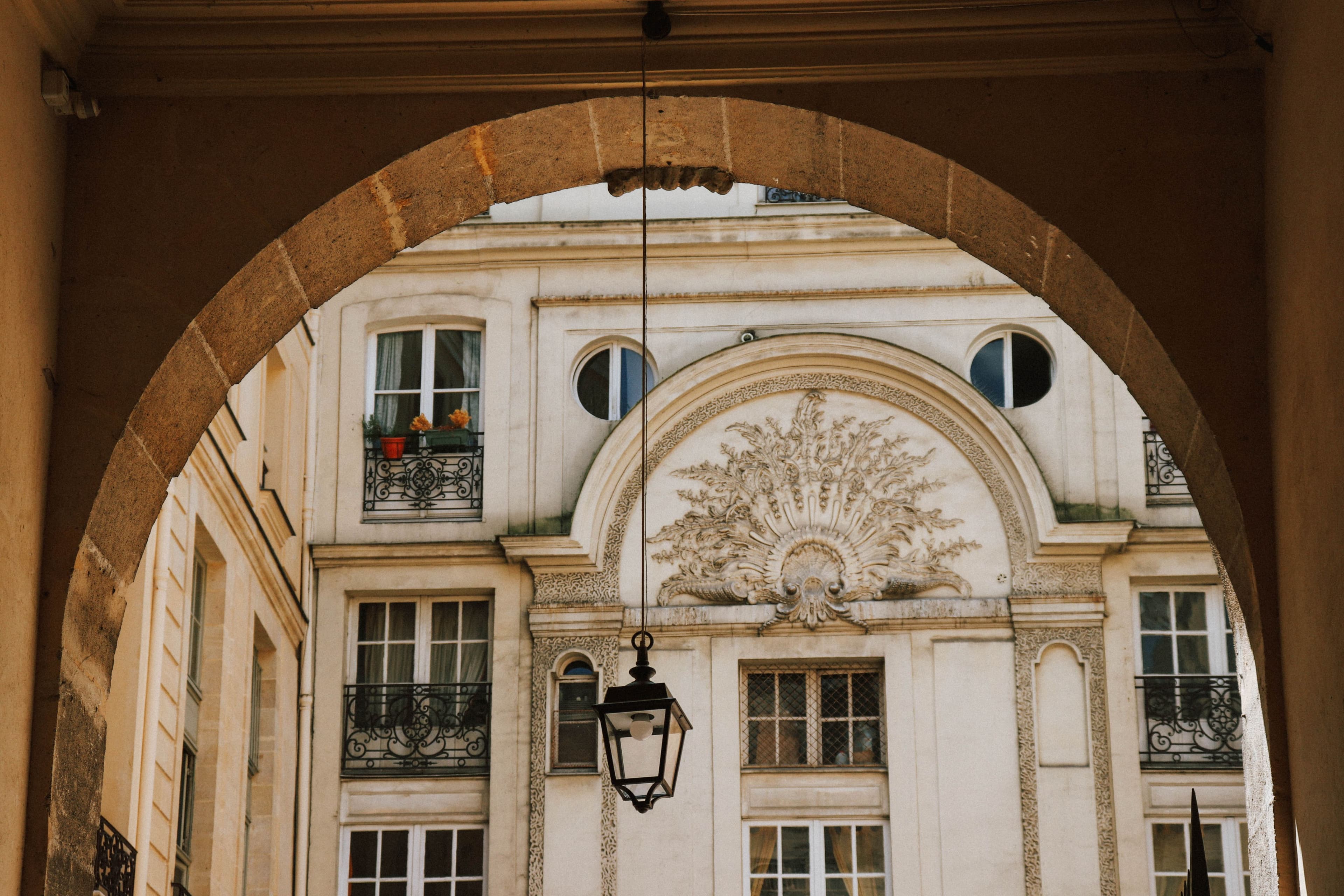 Cour parisienne encadrée d'une arche, illustrant la méthode Maison Victoire